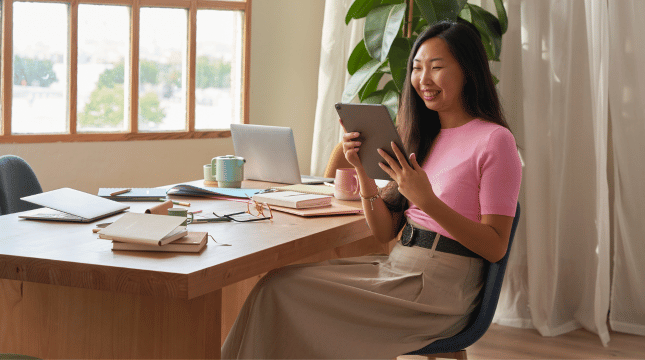 a femal professional sitting at a desk using a tablet.