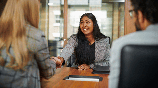 Two people shaking hands in an office after an interview.