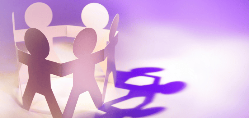 paper cut-outs of people holding hands on a purple background