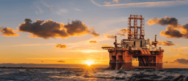 an oil rig in the middle of the ocean at sunset