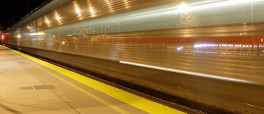 a person walking on the platform at night with a train in the background