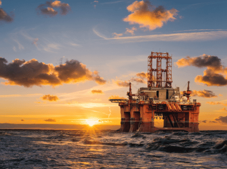 an oil rig in the middle of the ocean at sunset